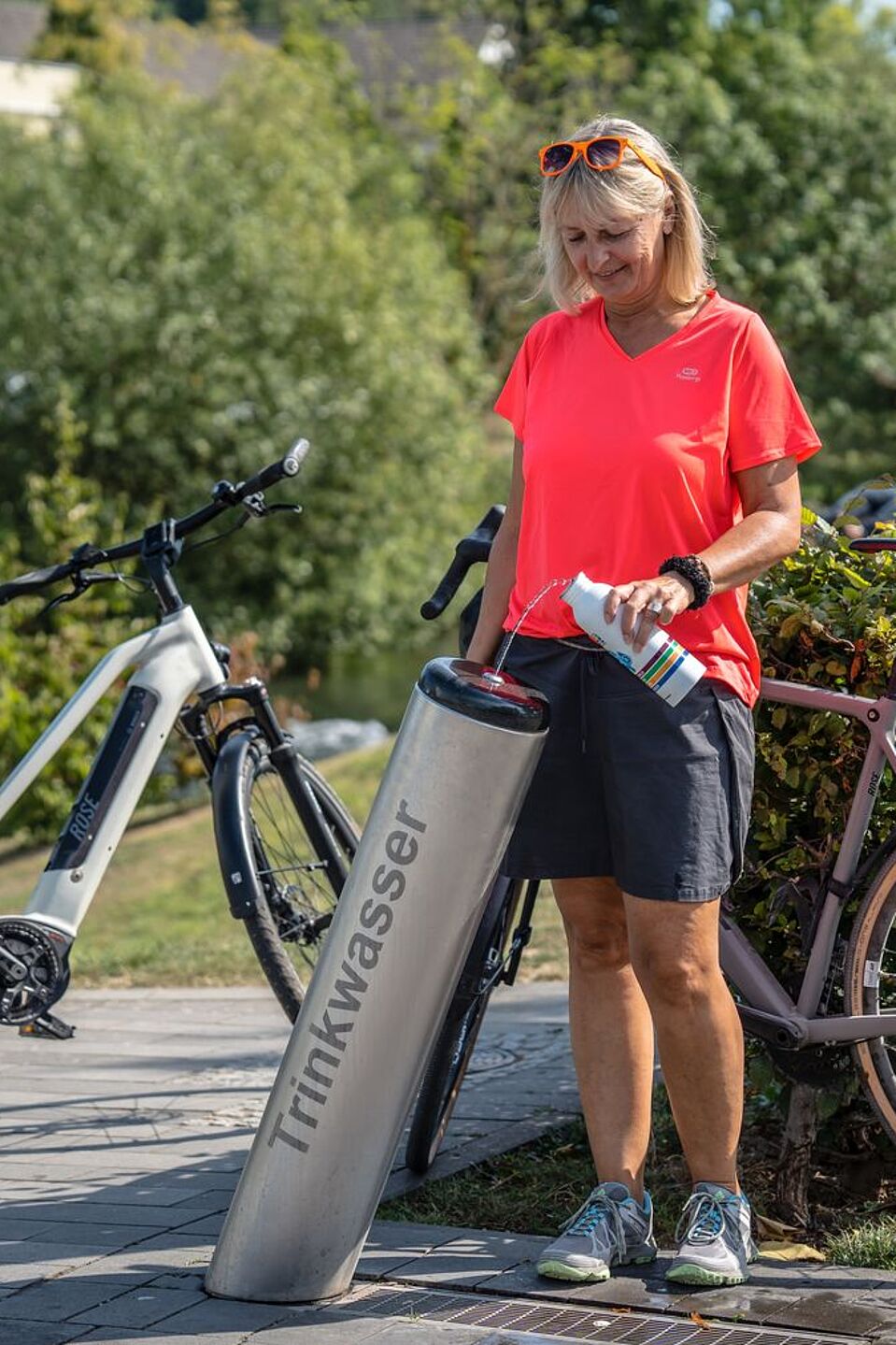 Wasserflaschen auffüllen am RuhrtalRadweg. Radfahrerin füllt Flasche an einem Trinkbrunnen des RuhrtalRadwegs auf.
